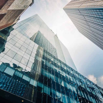 Image of three Skyscrapers taken on a low level with clouds in the background.